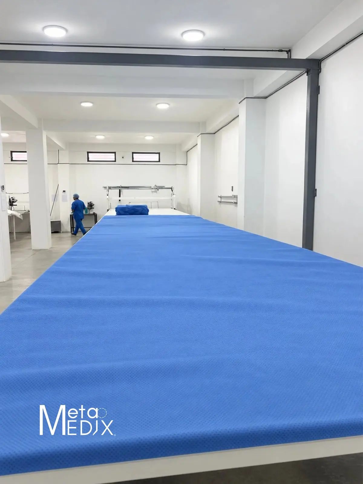 La mesa de corte de la planta, cubierta por la tela azul, con un operario al fondo